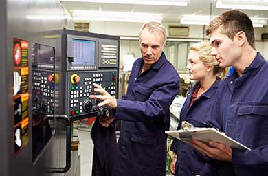 A Further Education lecturer showing two students how to operate a machine.